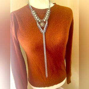 Long silver tone and rhinestone tassel necklace with gold starburst.